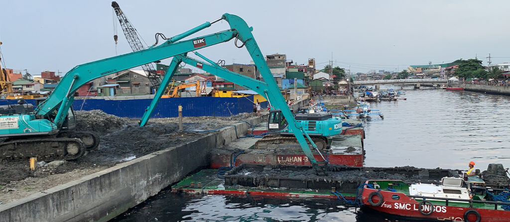 blue crane lifting garbage out of Pasig river